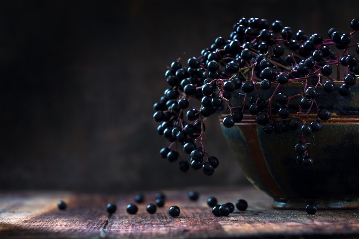 Μαύρα elderberries (sambucus nigra) σε ένα μπολ, σκοτεινό ρουστίκ ξύλο